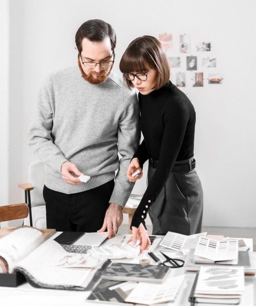 Two designers reviewing samples and color palettes for a creative project.