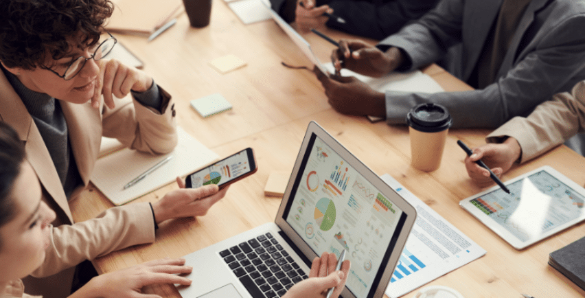 A diverse team discussing business analytics with charts displayed on a laptop.