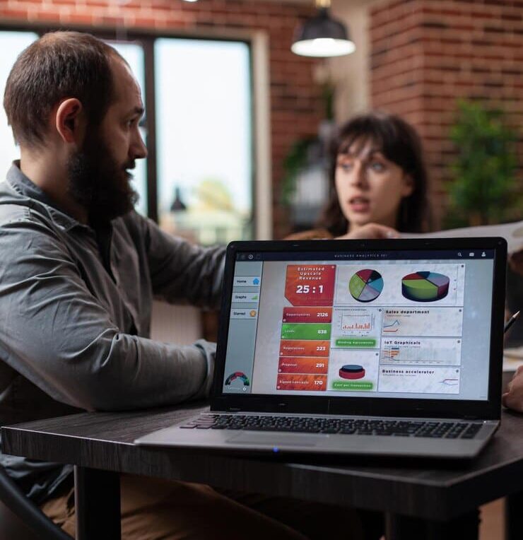 A laptop displaying company growth statistics and global business review charts.